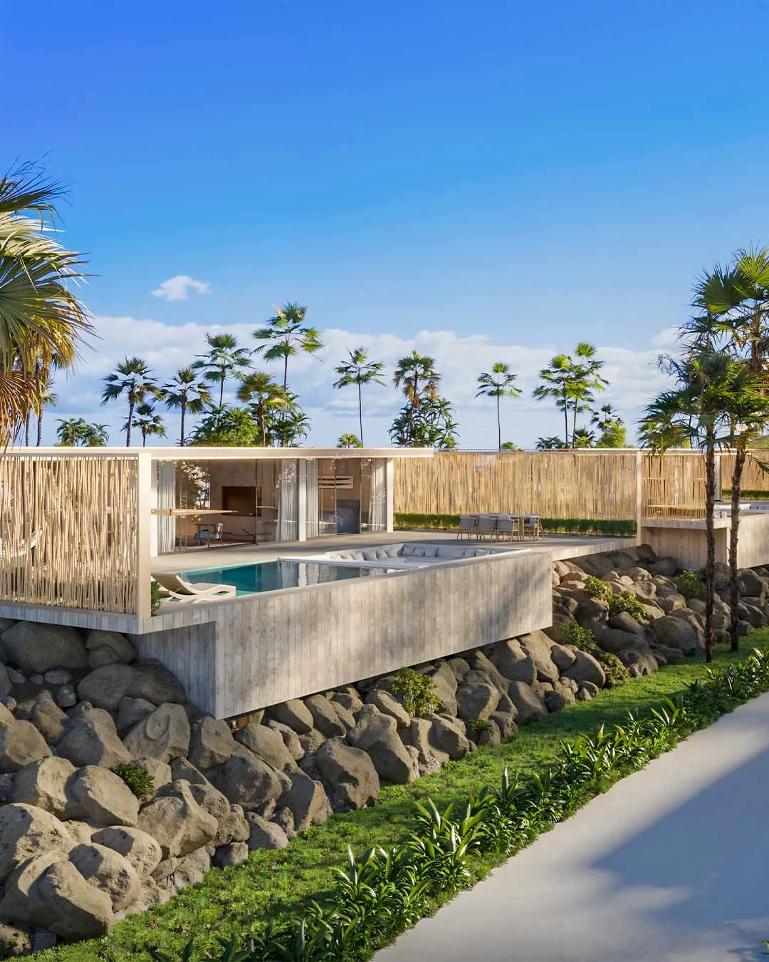 Pool terrace set above natural rock and landscaped greenery, with palm trees beyond